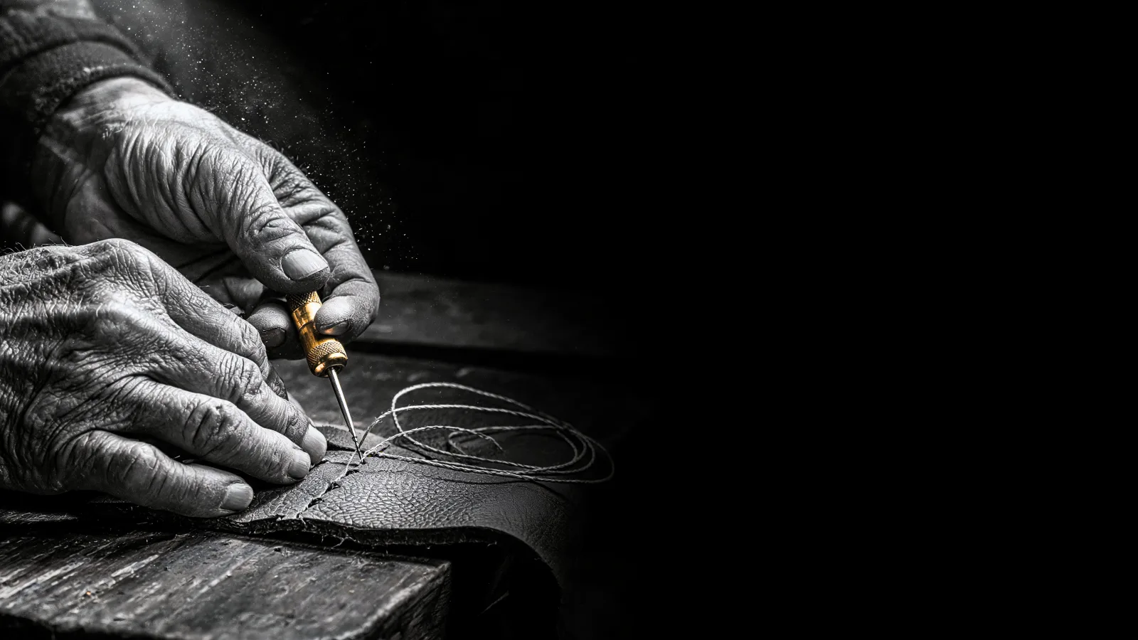 Hands at the bench — an artisan working full-grain leather in low afternoon light